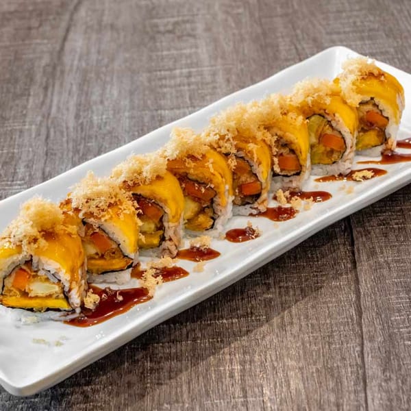 Wazabi Sushi's mango sushi roll with crispy topping and sauce on a white rectangular plate.