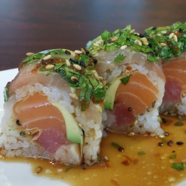 Wazabi Sushi's salmon and tuna sushi rolls with avocado, topped with greens and sesame seeds.