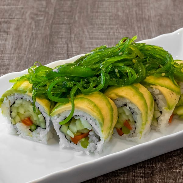 Wazabi Sushi's avocado and vegetable sushi rolls topped with bright green seaweed salad.