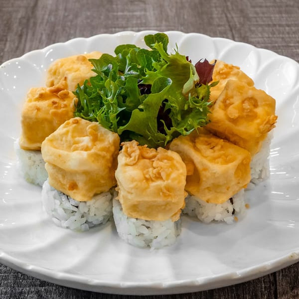 Wazabi Sushi's fried tofu sushi rolls with a fresh green salad garnish on a white plate.