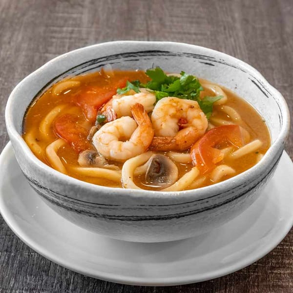Wazabi Sushi's shrimp and noodle soup with tomatoes, mushrooms, and cilantro in a white bowl.